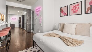 A modern hotel room with a bed, a sitting area with bar stools, and a kitchen area. - Charming 1-Bedroom Condo, 10 Minutes From Downtown Nashville (Nashville)