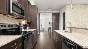 A modern kitchen with dark wooden cabinets, a stainless steel microwave, and a dishwasher. - Charming 1-Bedroom Condo, 10 Minutes From Downtown Nashville (Nashville)