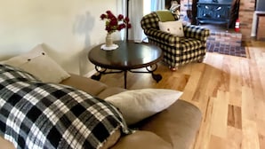 A living room with a sofa, a round table, and a fireplace. - Rapid River Retreat! Home sleeps 6, garage, fire pit (Rapid City)