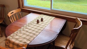 A dining table with a plaid tablecloth, two pinecones, and wooden chairs. - Rapid River Retreat! Home sleeps 6, garage, fire pit (Rapid City)