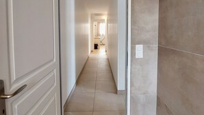 A hallway with a tiled floor and walls, leading to a room with a door. - Regarding a WITHDRAWN LISTING: BEAUTIFUL 3-STAR-RATED HOUSE IN LA COTINIERE (Saint-Pierre D Oleron)