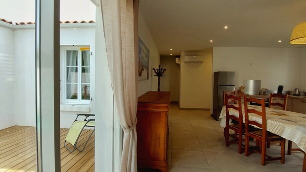 A modern kitchen with a dining area, wooden flooring, and a view through a sliding glass door. - Regarding a WITHDRAWN LISTING: BEAUTIFUL 3-STAR-RATED HOUSE IN LA COTINIERE (Saint-Pierre D Oleron)