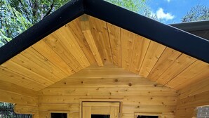Una cabaña de madera con techo a dos aguas, dos puertas y un pequeño porche.