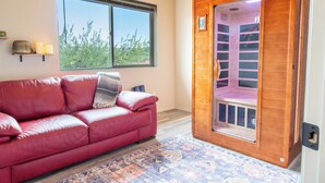 Ein rotes Ledersofa, eine Holzsauna und ein Fenster mit Blick auf Bäume.