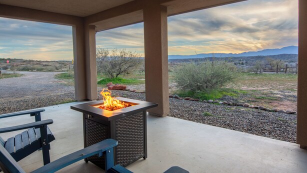 A covered patio with a fire feature, seating, and a view of the surrounding landscape. - Private Wine Country Retreat • 2 Suites & 2 Hot Tubs (Cornville)