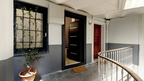 A hallway with a potted plant, a wooden door, and a white railing. - ✨ L'Instant Nîmois - Natural elegance in the heart of Nîmes ✨ (Nîmes)