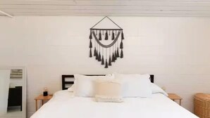Un lit bien fait, avec du linge de lit blanc, et une décoration murale au-dessus.