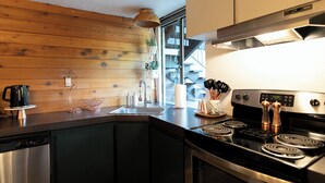 Une cuisine moderne avec des murs en bois, des appareils électroménagers en acier inoxydable et une grande fenêtre donnant sur un escalier.