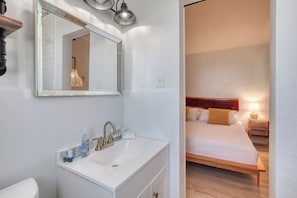 A bathroom with a white sink, mirror, and toilet. - Pineapple Shores Retro Inn (Daytona Beach Shores)