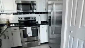 A modern kitchen with white cabinets, stainless steel appliances, and a black and white patterned floor. - Modern 2BR Apartment in Brickell, Central w Sea View (Miami)