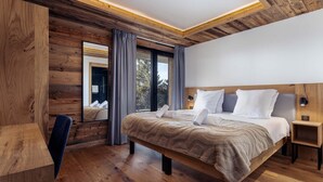 A modern bedroom with a wooden ceiling, a large bed, a desk, and a mirror. - Holiday Home in La Rosiere Near Ski Slopes (Montvalezan)