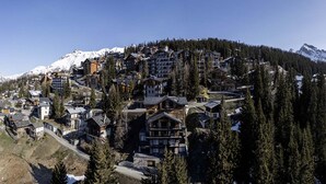 A mountainous resort town with multiple buildings, including a prominent lodge with a large balcony and a mountain backdrop. - Holiday Home in La Rosiere Near Ski Slopes (Montvalezan)