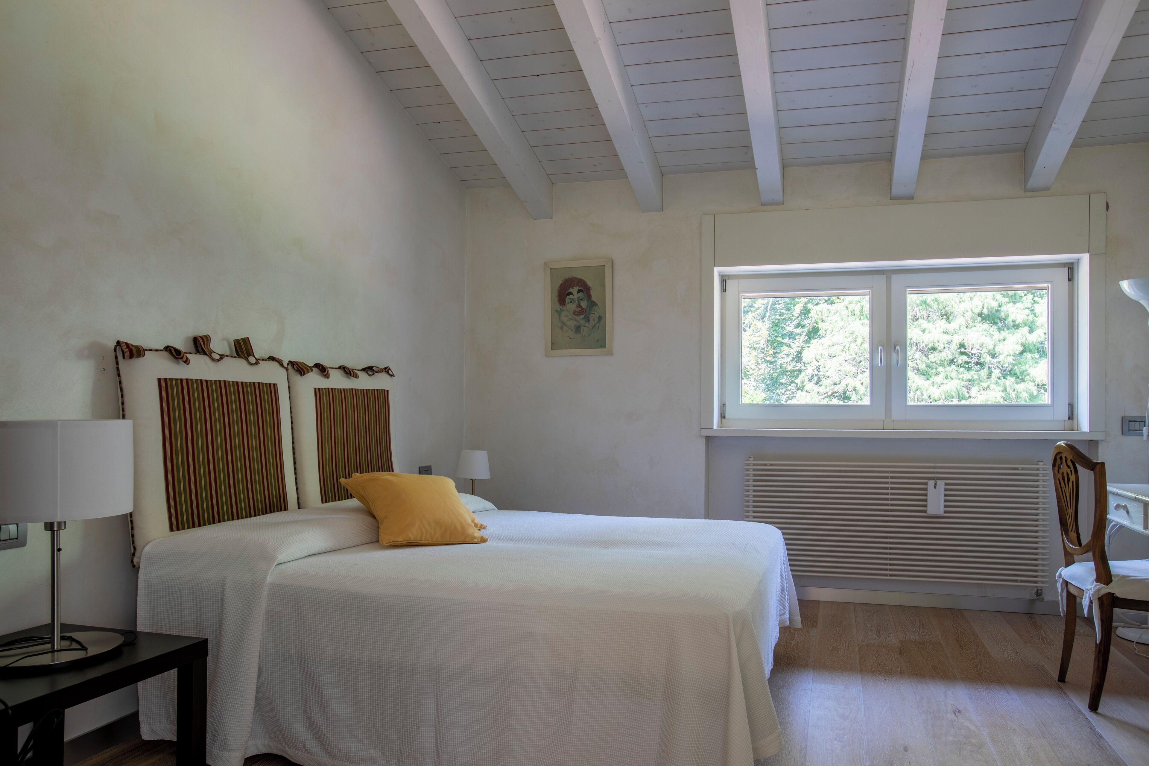 Ein Schlafzimmer mit Bett, Fenster, Heizkörper und Stuhl.