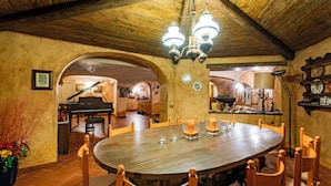 A dining area with a round wooden table, chairs, and a chandelier. - Villa La Fortezza - Six Bedroom Villa, Sleeps 12 (Dormelletto)