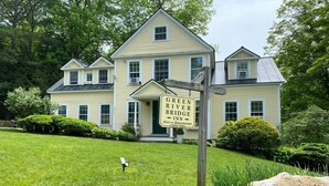 A large, two-story house with a sign for the Green River Bridge Inn, indicating it offers bed and breakfast services. - Private bedroom in the Green River Bridge Inn. A full breakfast is included. (Guilford)