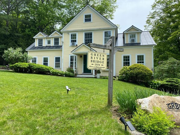 A large, two-story house with a sign for the Green River Bridge Inn, indicating it offers bed and breakfast services. - Private bedroom in the Green River Bridge Inn. A full breakfast is included. (Guilford)