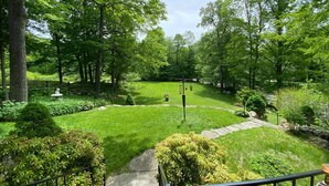 A lush garden with a well-maintained lawn, stone pathways, and various shrubs. - Private bedroom in the Green River Bridge Inn. A full breakfast is included. (Guilford)