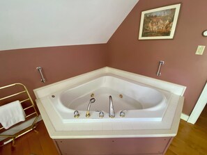 A corner bathroom with a freestanding bathtub, a towel rack, and a painting on the wall. - Private bedroom in the Green River Bridge Inn. A full breakfast is included. (Guilford)