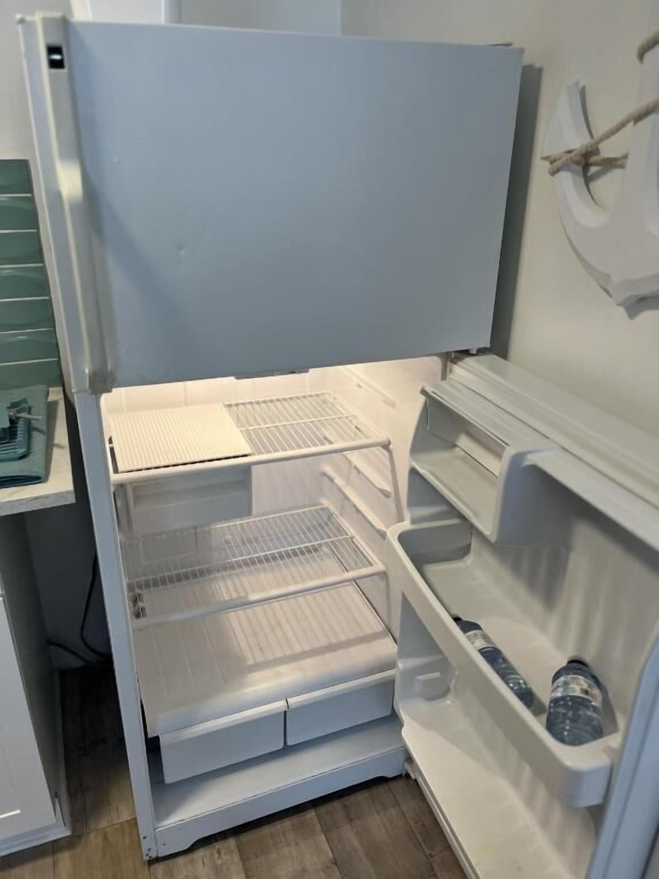 Geladeira branca com várias prateleiras e compartimento para congelador.