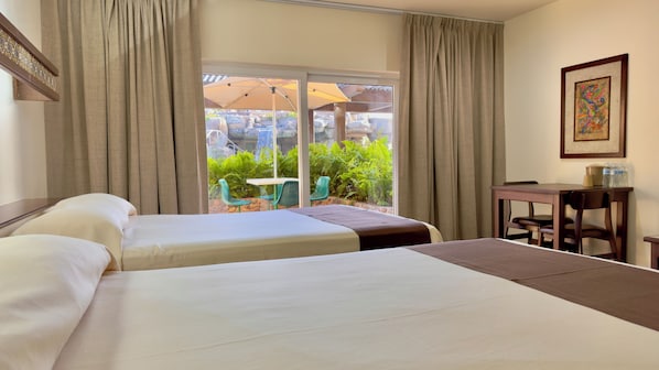 A hotel room with two beds, a desk, and a view of an outdoor garden. - Hotel Playa Mazatlan - All Inclusive (Mazatlán)