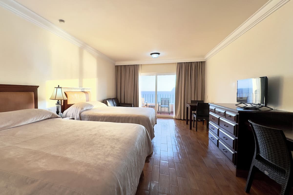 A hotel room with two beds, a desk, a chair, and a television.