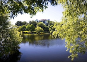 A house surrounded by trees and a calm lake.