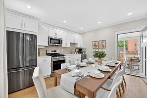Una cocina moderna con armarios blancos, electrodomésticos de acero inoxidable y una zona de comedor preparada para seis personas.