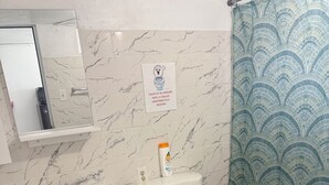 A bathroom with a white sink, toilet, and a shower curtain with a wave pattern. - The residence 2 (Cabo Rojo)
