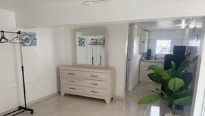 A room with a wooden dresser, a mirror, a coat rack, and a potted plant. - The residence 2 (Cabo Rojo)
