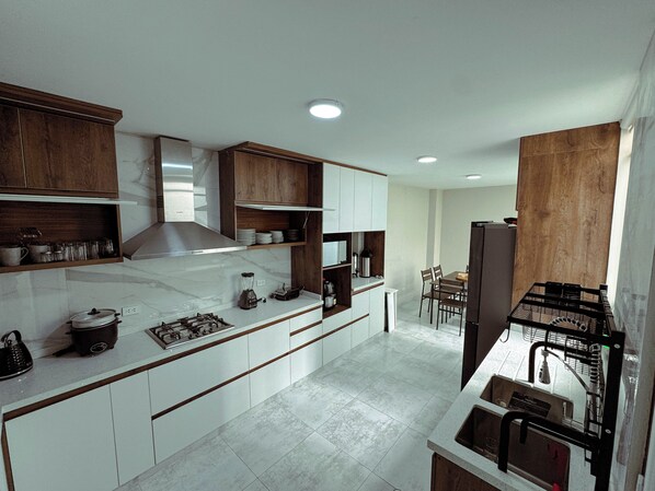 A modern kitchen with white cabinets, a central island, and a dining area with chairs.