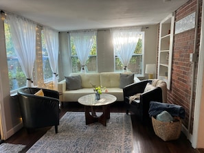 Una sala acogedora con un sofá, dos sillones, una mesa de centro y una estantería de ladrillo.