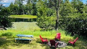 Ein Picknickplatz mit Tisch und Stühlen, umgeben von Gras und Bäumen.
