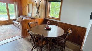 Ein gemütliches Blockhaus-Interieur mit einem Holzesstisch, Stühlen, einer Couch und einem Kamin.