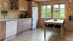 A kitchen with wooden cabinets, a dishwasher, a coffee maker, and a dining table with chairs.