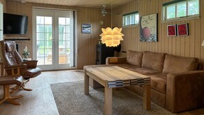 A cozy living room with a brown leather sofa, a wooden coffee table, and a television on the wall.