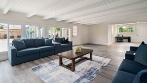 A spacious living room with a large sofa, a coffee table, and a view of the outside. - Newly Renovated! OC Retreat Near Disney & Beaches (Fountain Valley)