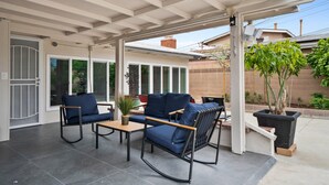 A covered patio area with a seating arrangement including a sofa and chairs, a small table, and a potted plant. - Newly Renovated! OC Retreat Near Disney & Beaches (Fountain Valley)