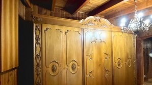 A room with a wooden wardrobe, a bed, and a chandelier.