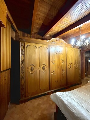 Um quarto com guarda-roupa de madeira, uma cama e um candelabro.