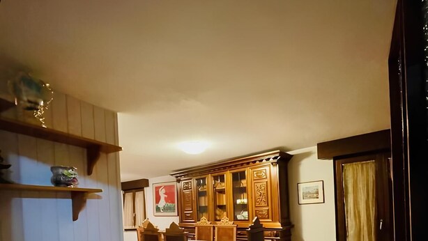 A dining area with a wooden table and chairs, a kitchen counter with a sink, and a patterned floor.