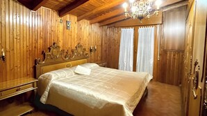 A spacious bedroom with a large bed, wooden walls, and a chandelier.