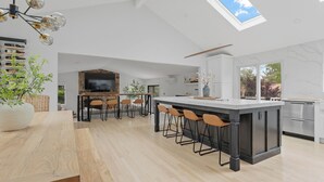 A modern kitchen with a large island, bar stools, a stone fireplace, and a skylight. - Beautiful and Spacious  Home with WiFi and AC in delightful Narragansett (Narragansett)