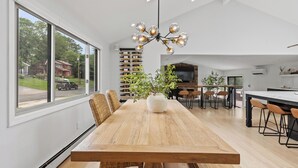 A modern dining area with a wooden table, wicker chairs, a large window, and a unique chandelier. - Beautiful and Spacious  Home with WiFi and AC in delightful Narragansett (Narragansett)