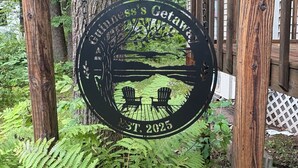 A wooden pergola with a black sign stating "Chill's Getaway" and "EST. 2025" surrounded by ferns and trees.