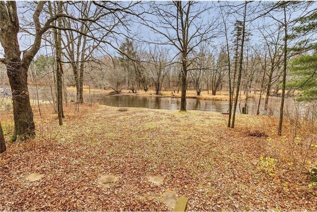 Eine natürliche Landschaft mit einem Teich, umgeben von Bäumen und herabgefallenen Blättern.