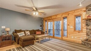 A cozy log cabin interior with a sofa, coffee table, and a stone fireplace.