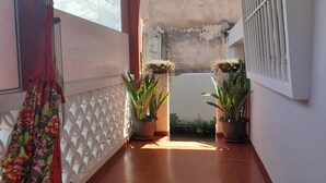 Un pasillo con suelo de baldosas, una cortina roja y plantas en macetas.