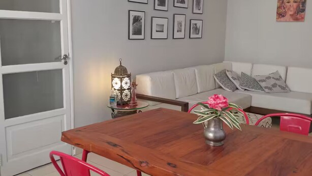 Un comedor con una mesa de madera, sillas rojas, un sofá blanco y una pared decorada con cuadros.