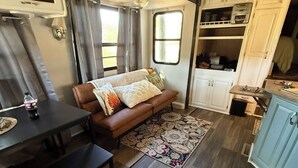 Interior compacto de autocaravana con sofá, mesa de comedor y kitchenette.