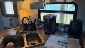 Una cocina compacta con lavamanos, cafetera y ventana con vistas.